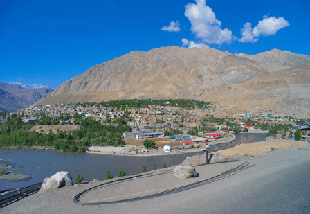 Kargil city from the outskirts, Jammu and Kashmir. Aerial view of city with mountains behind and river at forefront.