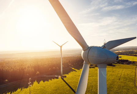 Photo of two wind turbines across sunny landscape