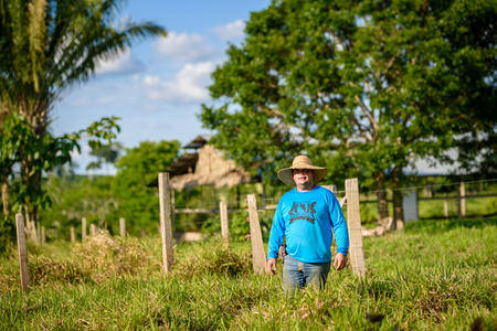 Photo of Peruvian farmer in a field. Tall grass and trees in backdrop
