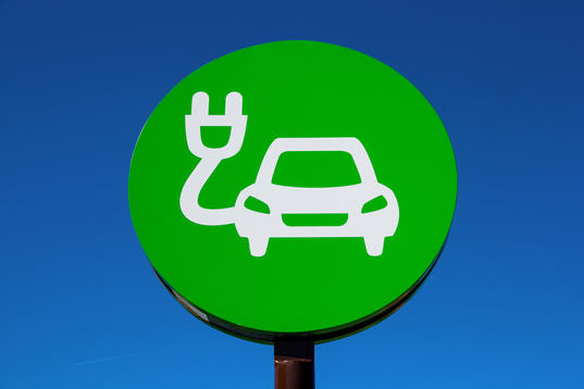 Green sign of drawn car with electric plug on blue background